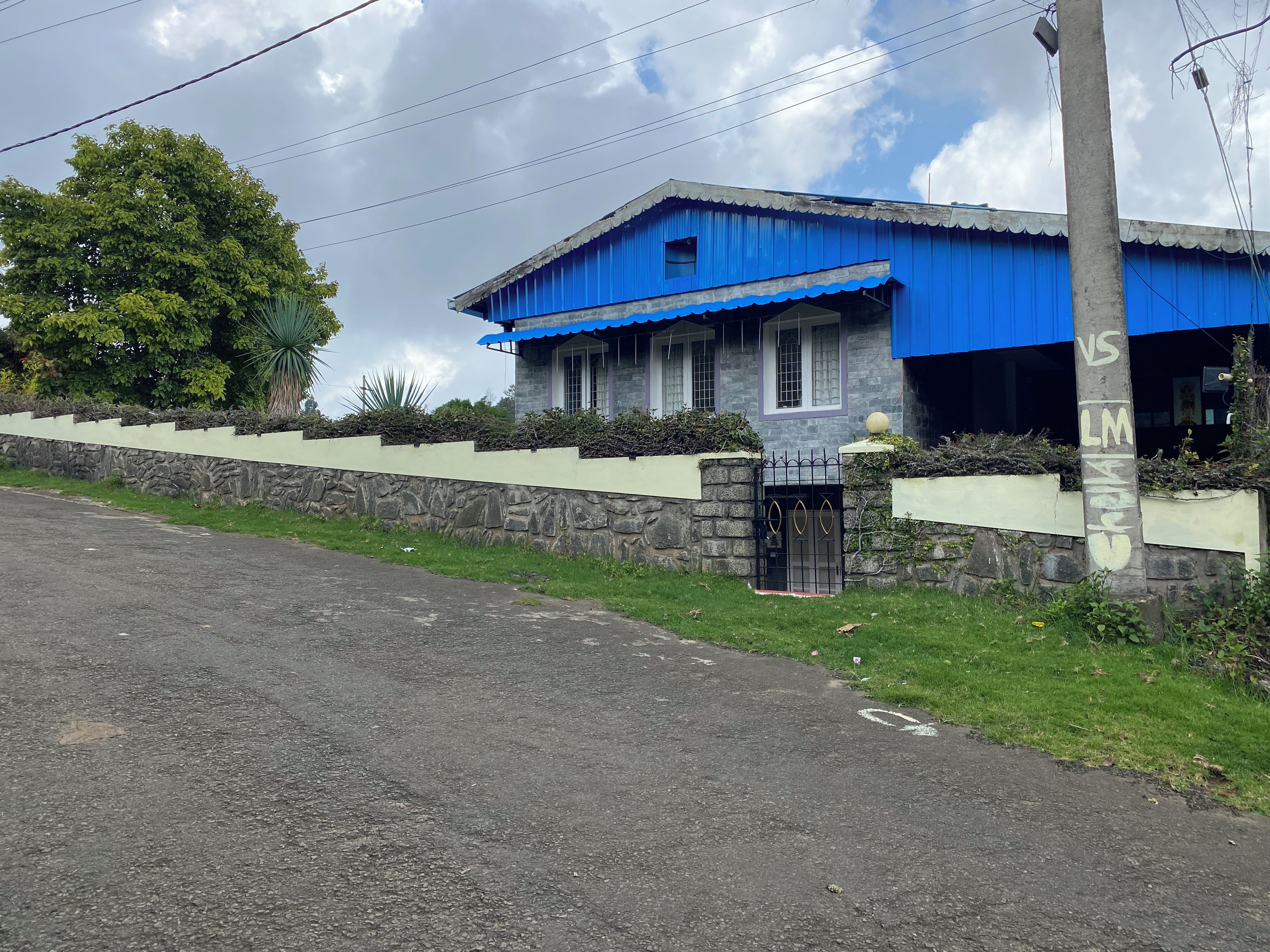 A two-story building with a blue roof and a stone wall.