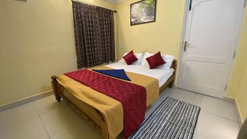 Una habitación de hotel con cama, una puerta, una ventana con cortinas y un cuadro en la pared.