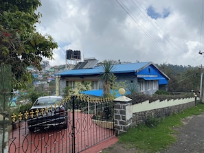 A house with a blue roof, a gated driveway, and a parked car.