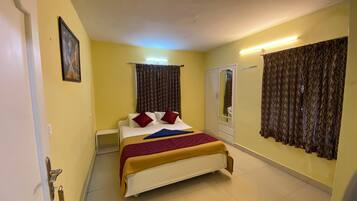Quarto de hotel com uma cama, um guarda-roupa, um espelho e cortinas.