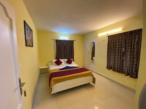 A hotel room with a bed, a wardrobe, a mirror, and curtains.