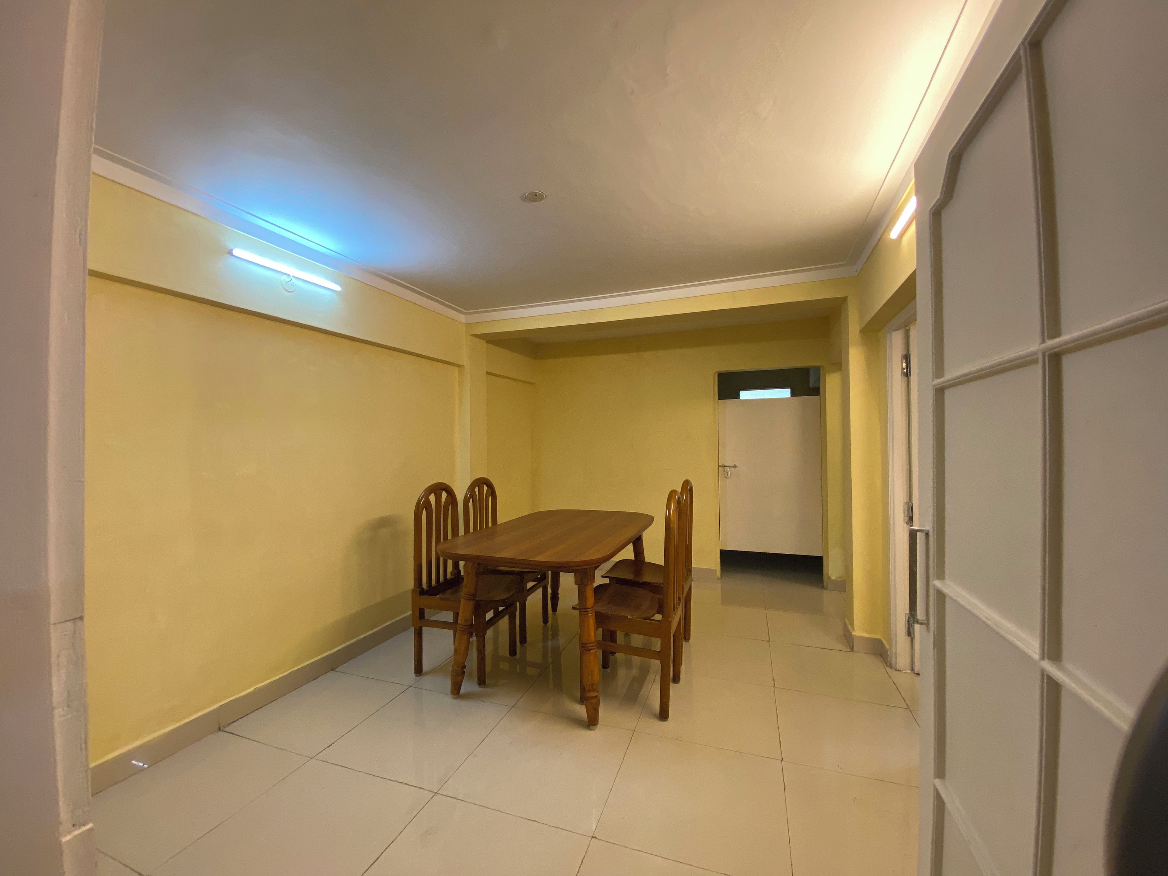 A room with a dining table and chairs, a door, and a light fixture on the ceiling.