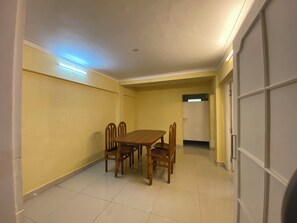 Quarto com mesa de jantar e cadeiras, uma porta e luminária no teto.