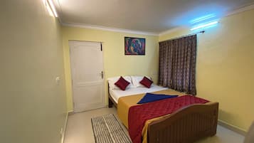 A bedroom with a bed, a door, a painting, curtains, and a floor mat.