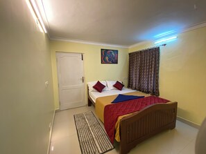 Quarto com cama, porta, quadro, cortinas e tapete no chão.