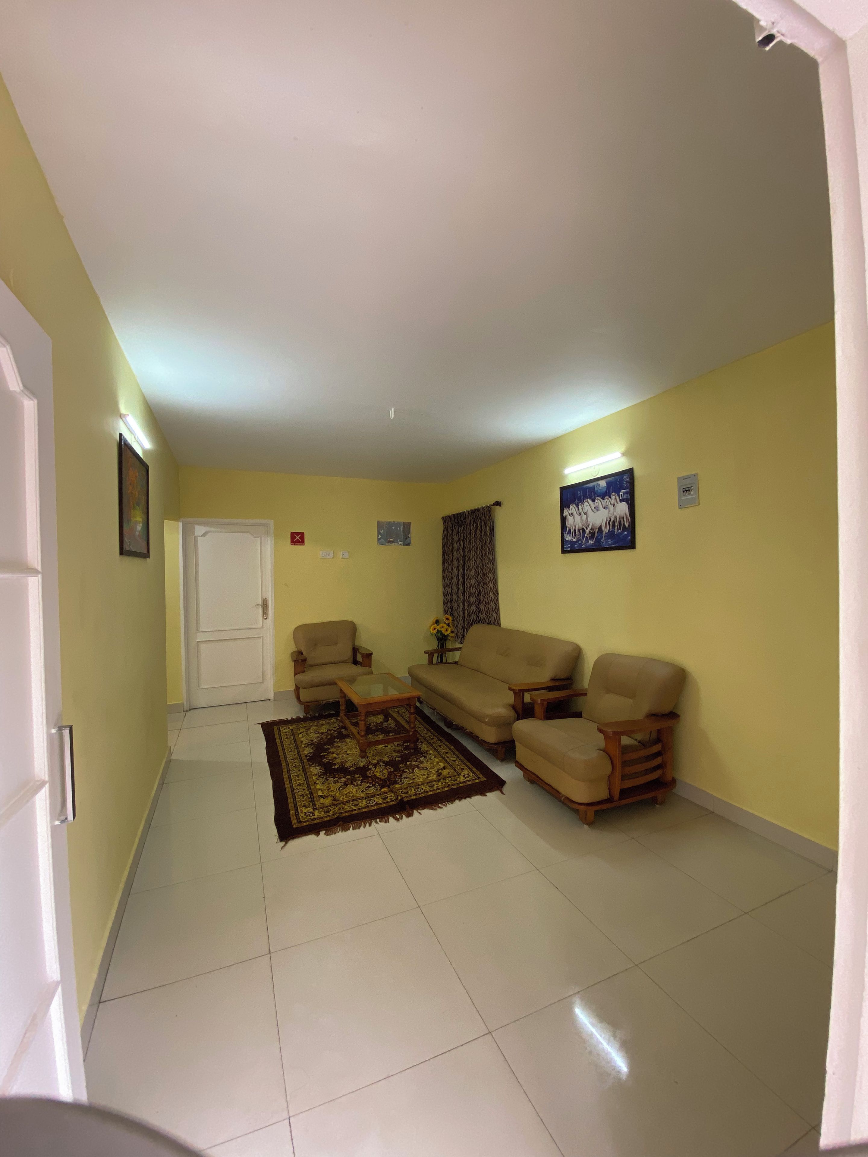 Una sala de estar con un sofá, sillones, una mesa de centro y un tapete estampado.