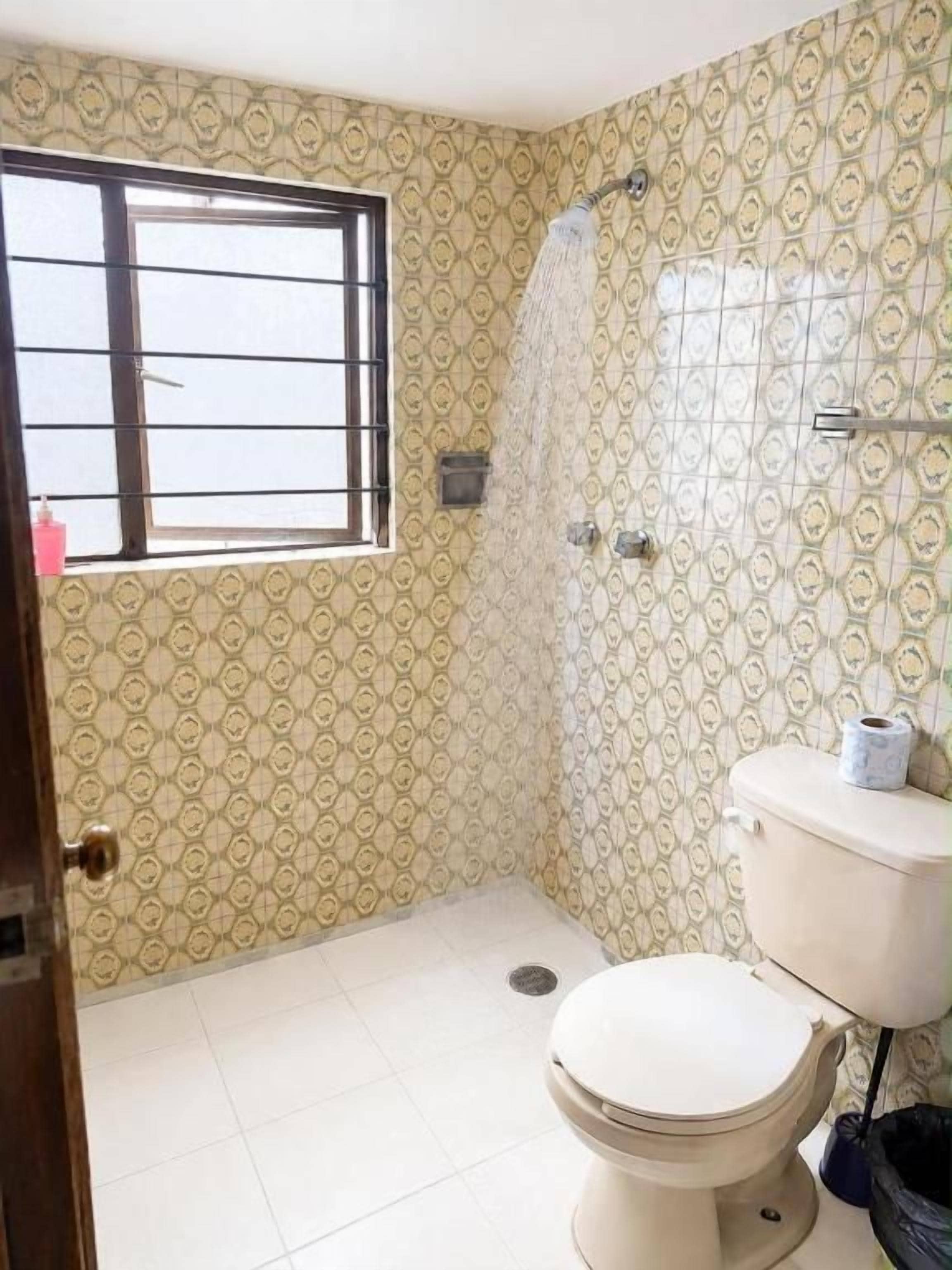 Un baño con inodoro, ducha y ventana.