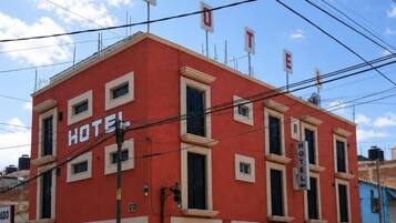 Punainen rakennus, jossa on kyltti, jossa lukee ”HOTEL”, useita ikkunoita ja selvästi näkyvä sisäänkäynti.
