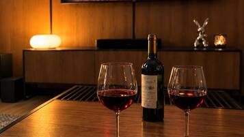 A wooden table with two wine glasses and a bottle, a fireplace, and a television mounted on the wall.