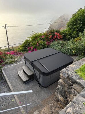 Ein Outdoor-Grill mit schwarmem Deckel, umgeben von einem Garten mit verschiedenen Pflanzen und Blumen.