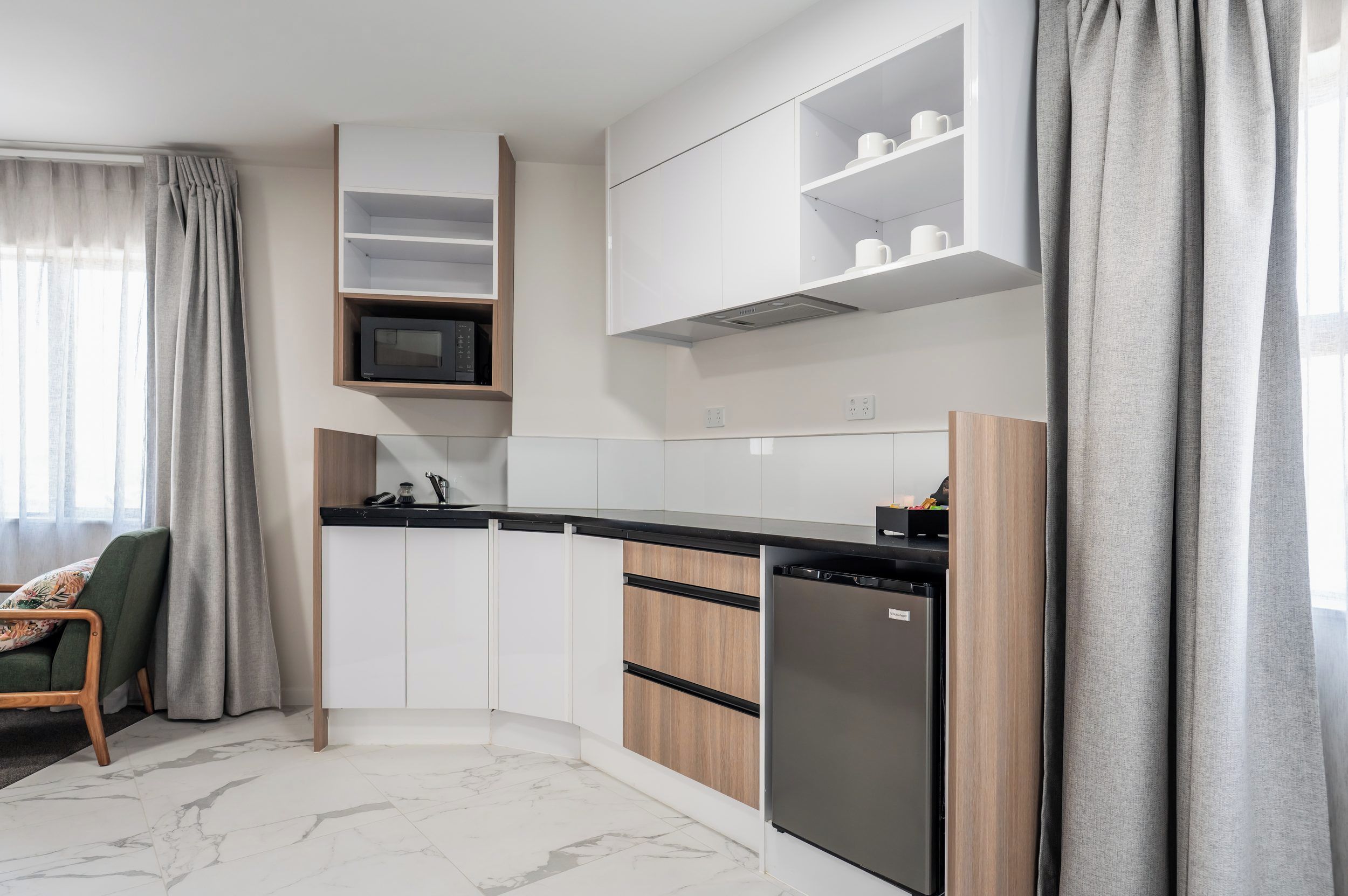 A modern kitchen with white cabinets, a black countertop, and a built-in dishwasher.