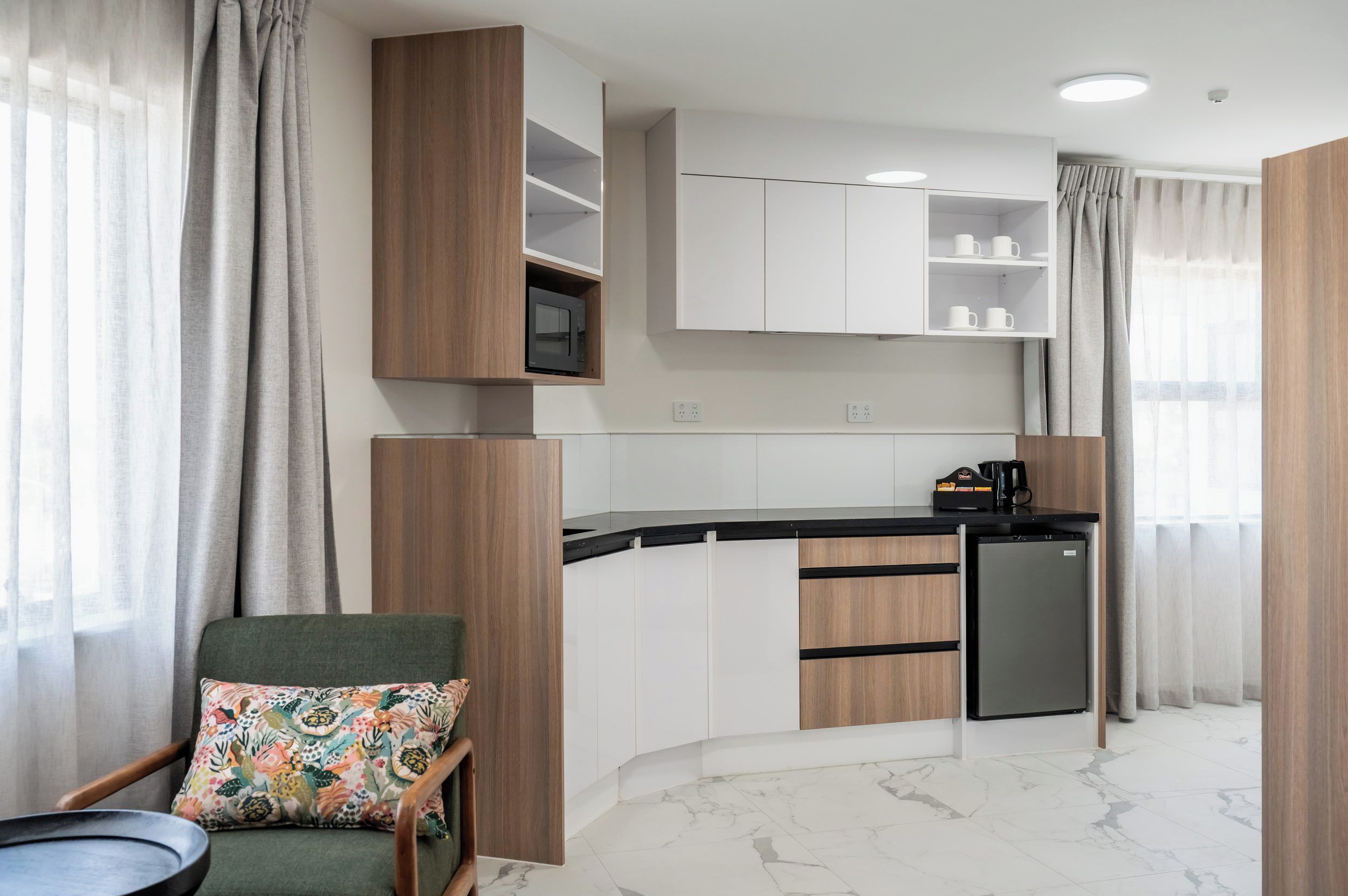 A compact kitchen with a microwave, coffee maker, and a refrigerator.