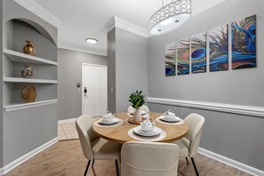 A dining area with a round table, chairs, and a white door in the background. - Stylish 2BR | Pool | Near Universal & Disney (Orlando)