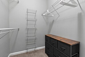 A closet with metal wire shelves and a wooden dresser. - Stylish 2BR | Pool | Near Universal & Disney (Orlando)