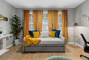A bedroom with a bed, curtains, a plant, a lamp, and a chair. - Stylish 2BR | Pool | Near Universal & Disney (Orlando)