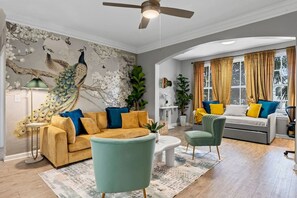 A living room with a sofa, armchairs, a coffee table, and a ceiling fan. - Stylish 2BR | Pool | Near Universal & Disney (Orlando)