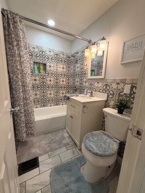A bathroom with a bathtub, toilet, sink, and a shower area. - Cozy 2-bedroom homeNear Downtown and Speedway (Indianapolis)