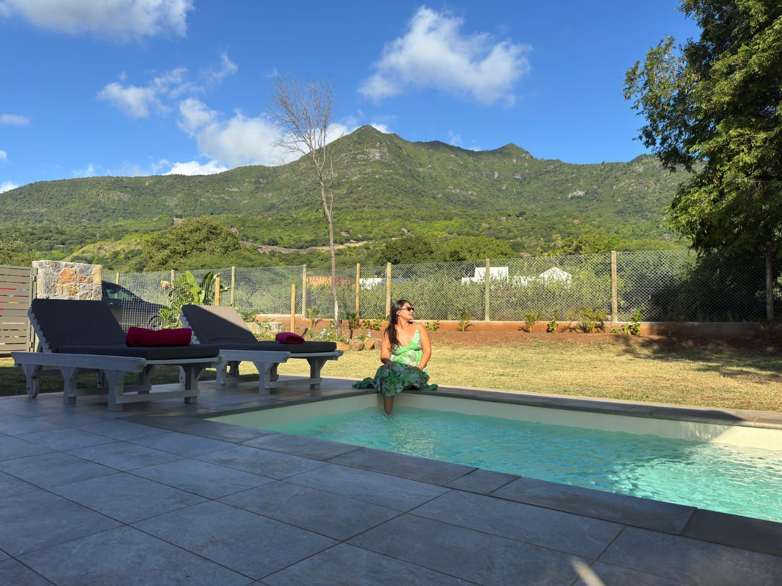 Une piscine avec des chaises longues et une personne assise au bord de la piscine.