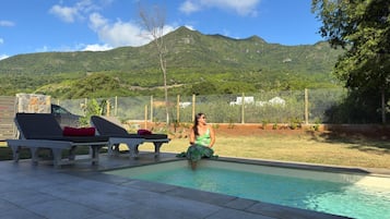 Une piscine avec des chaises longues et une personne assise au bord de la piscine.