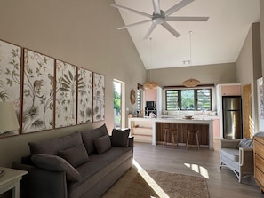 A modern kitchen with a central island, a ceiling fan, and a dining area with a sofa and chairs.