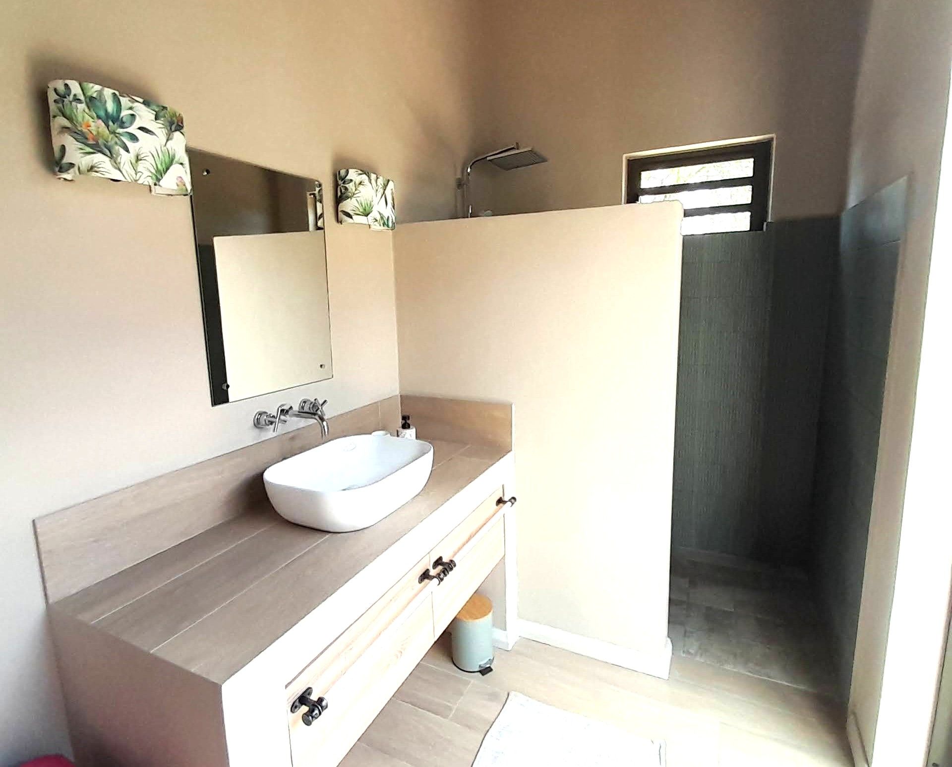 A bathroom with a white sink, a mirror, and a shower area.