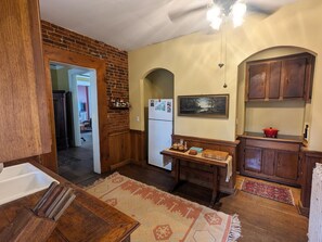 A kitchen with wooden cabinets, a refrigerator, a dining table, and a rug. - Long Term Rental for Workgroups near Downtown (Hannibal)