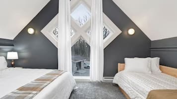 A bedroom with two beds, a large window, and a view of the outdoors.