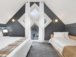 Quarto com duas camas, uma janela grande e vista para o exterior.