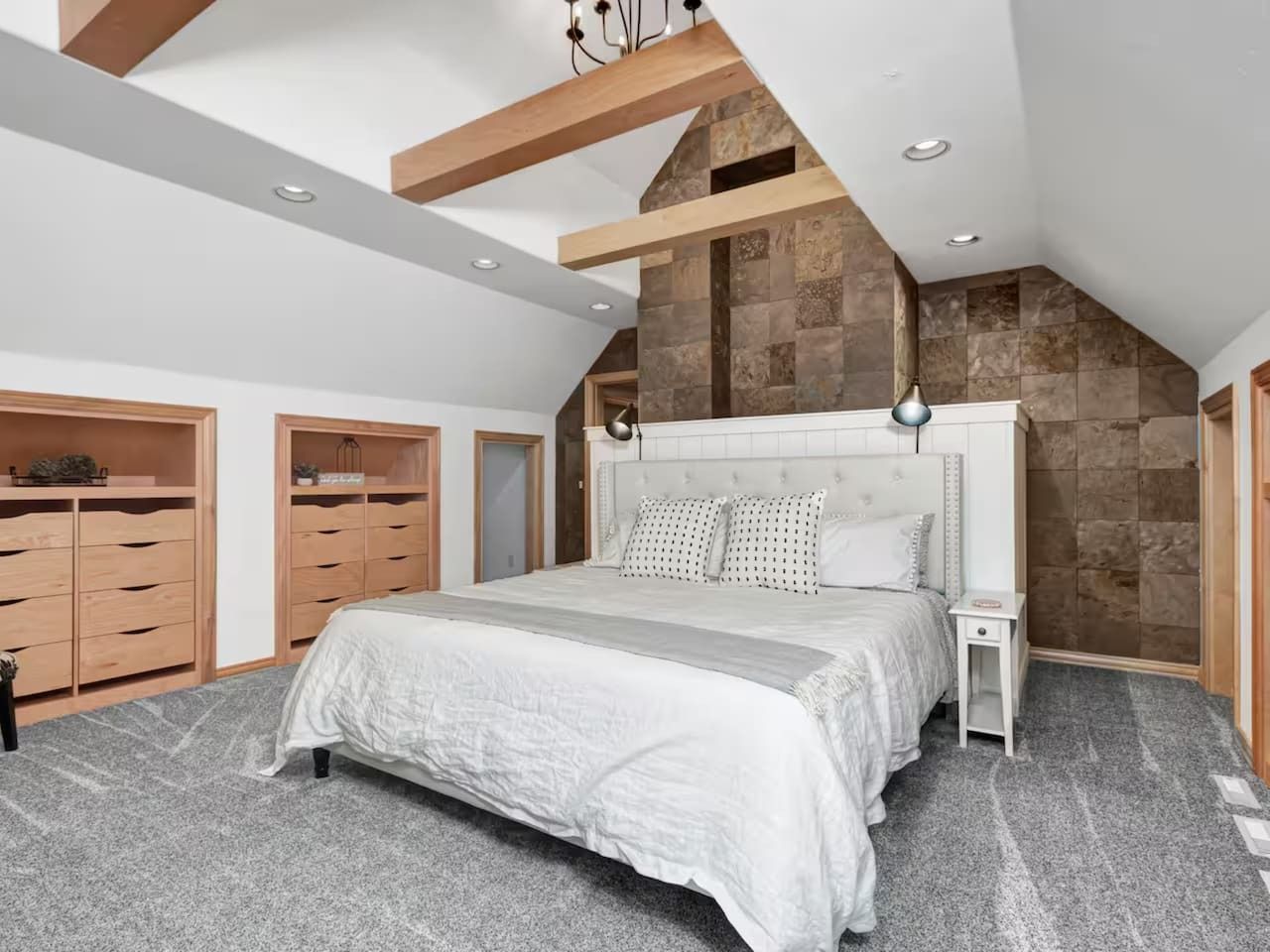 Un dormitorio con una cama grande, un armario de madera y una pared de acento de piedra.
