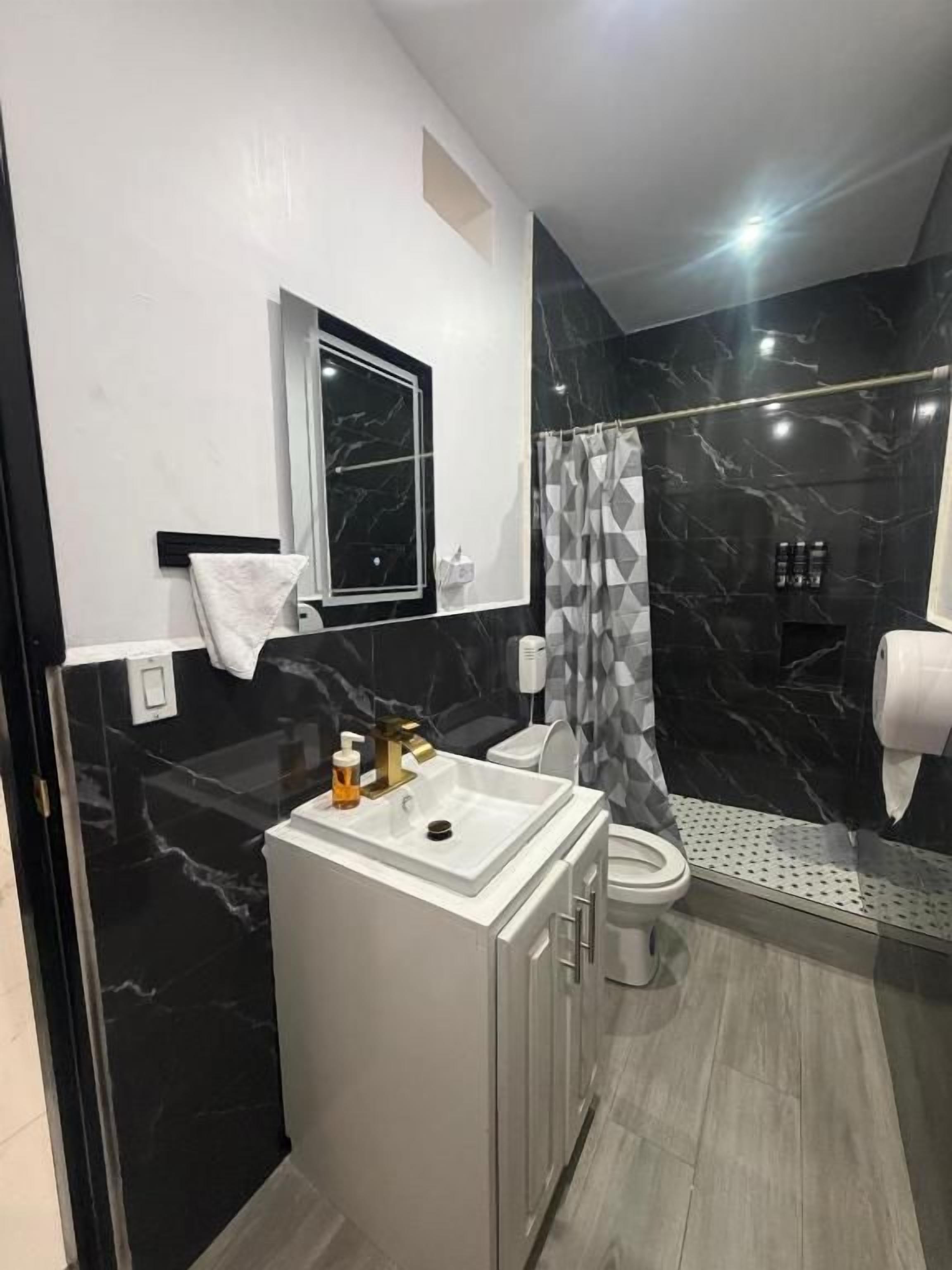 A modern bathroom with a marble vanity, a toilet, and a shower area.