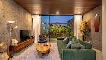 A modern living room with a green sofa, a wooden coffee table, and a TV on a wooden cabinet.