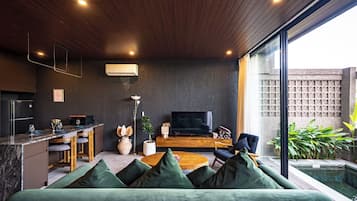 Una sala moderna con sofá, televisor y zona de comedor.