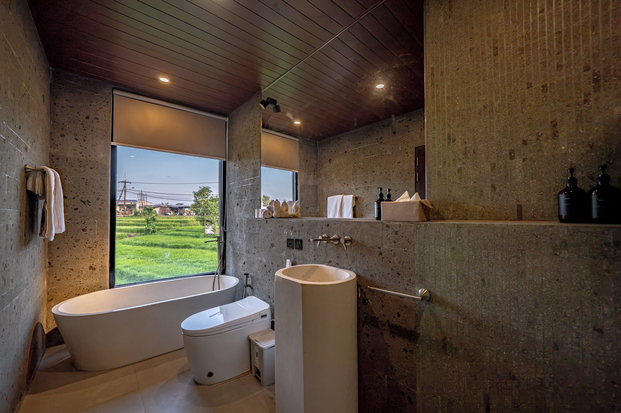 Un baño moderno con una bañera independiente, un inodoro y un lavamanos grande.