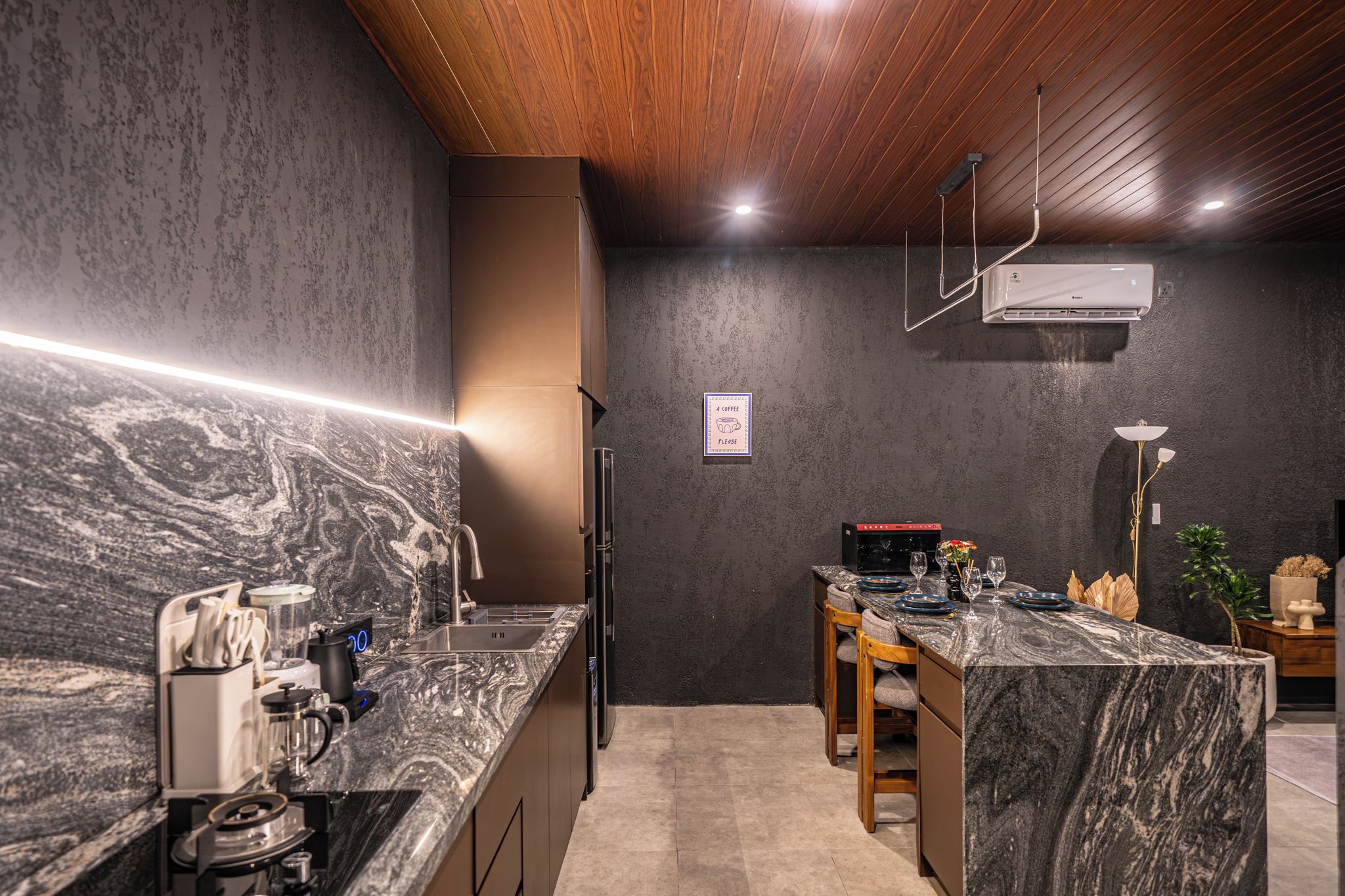A modern kitchen with a marble countertop, wooden ceiling, and a coffee sign on the wall.
