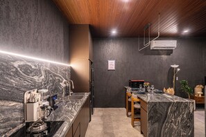 Una cocina moderna con encimera de mármol, techo de madera y un cartel que dice 'café' en la pared.