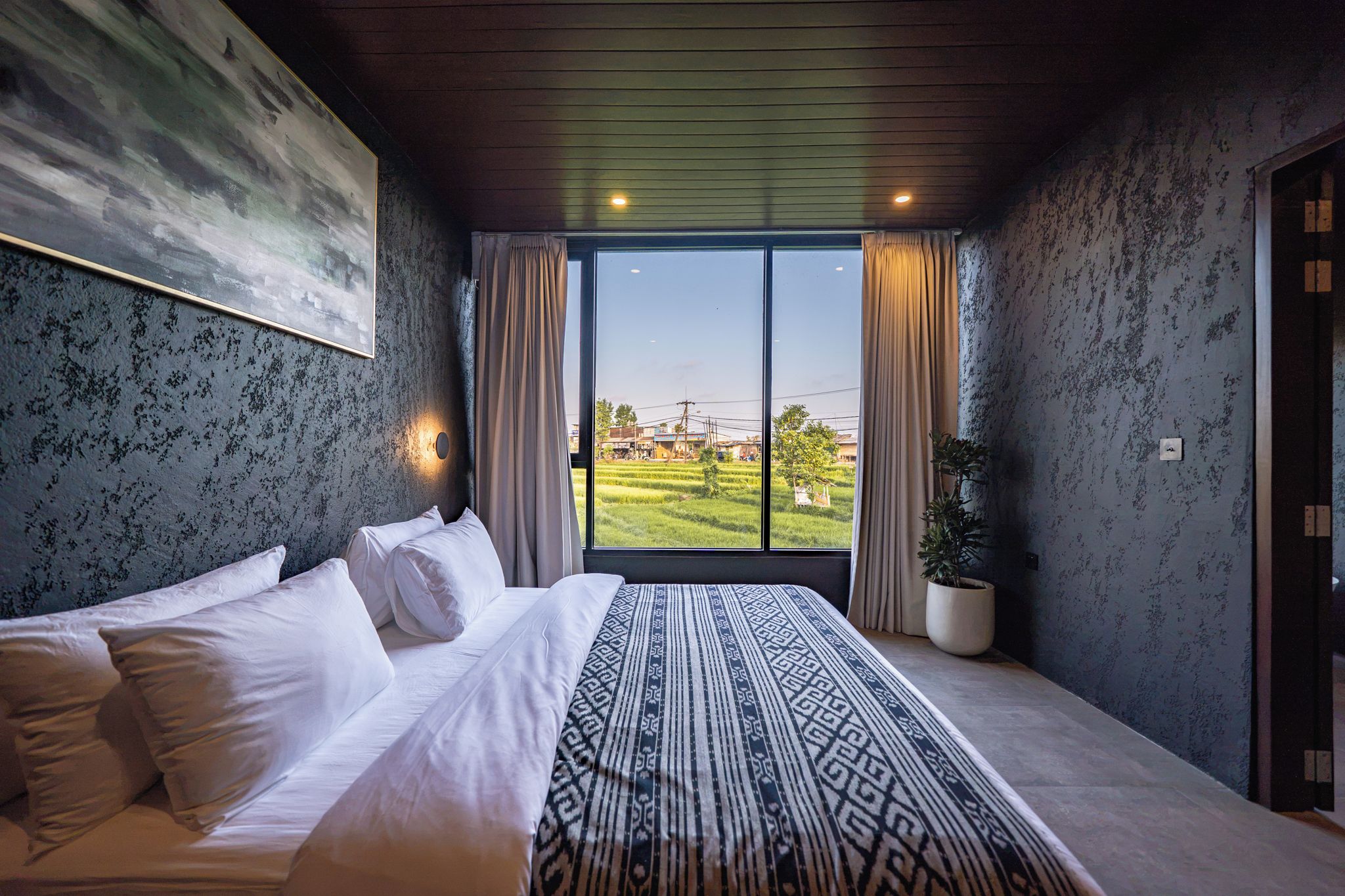 Een slaapkamer met een groot bed, uitzicht op een groen landschap en een modern design.