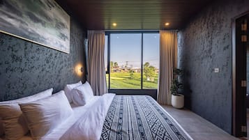 Een slaapkamer met een groot bed, uitzicht op een groen landschap en een modern design.