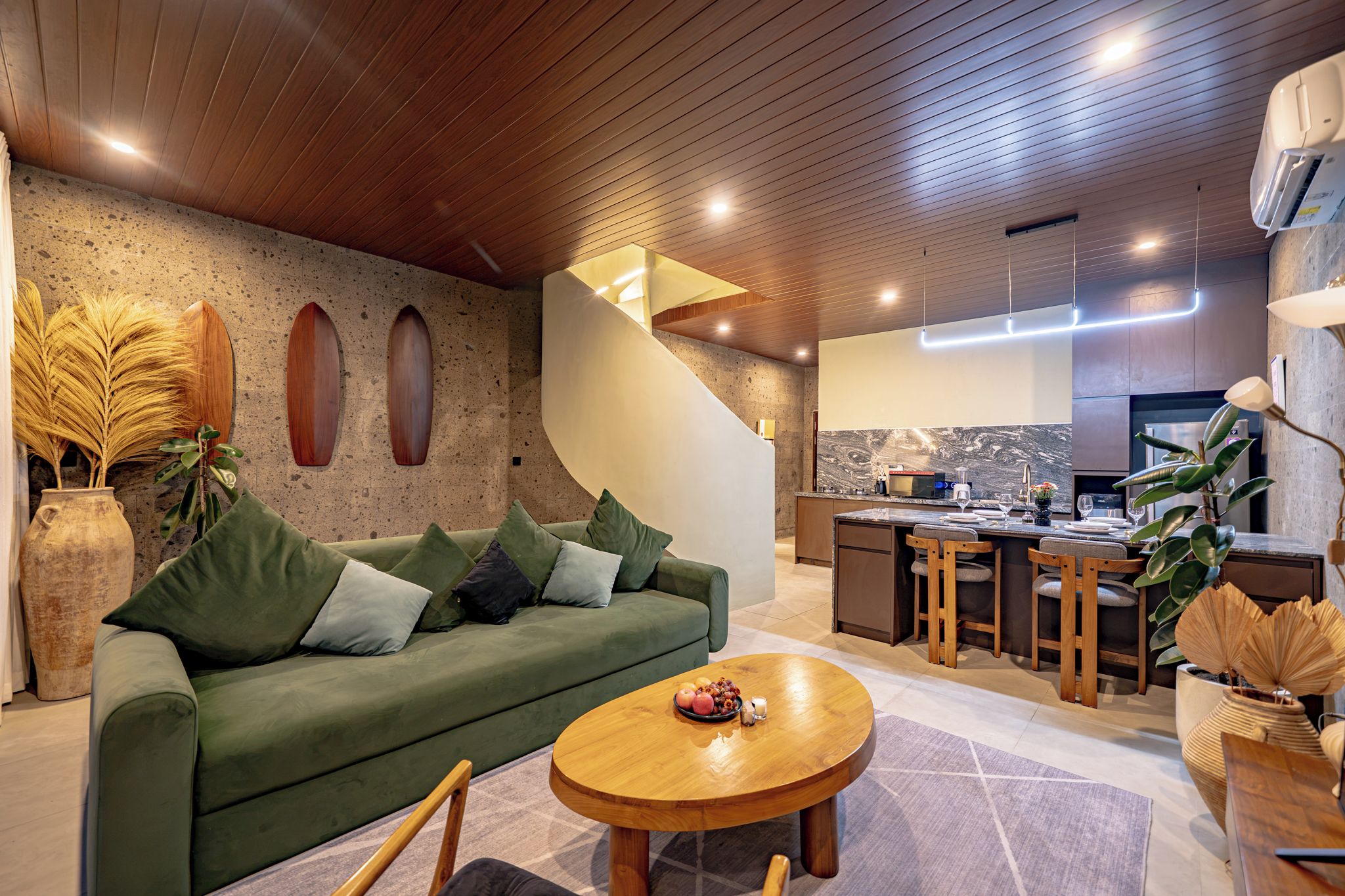Een modern interieur met een groene bank, een houten salontafel, een keukenhoek en een trap.