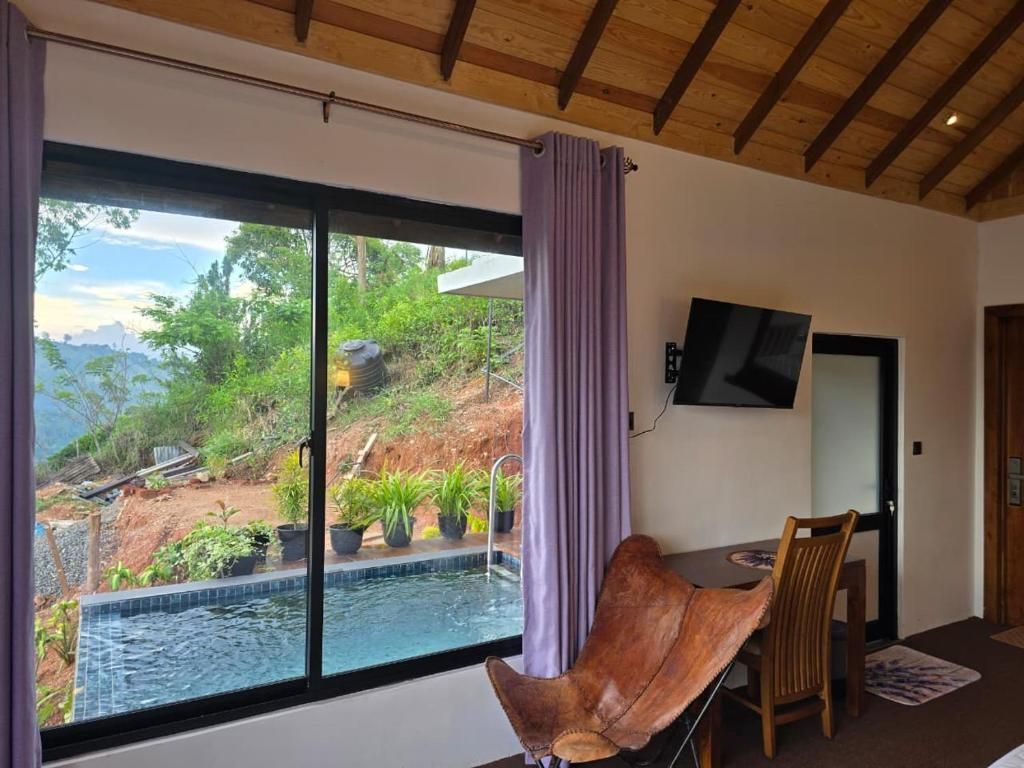 A room with a large window, a flat-screen TV mounted on the wall, a wooden ceiling, and a dining area with a table and chairs.