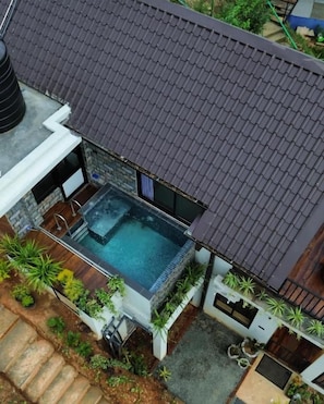 A rooftop swimming pool with a stone wall and plants around it. - Dewpoint Ella (Ella)