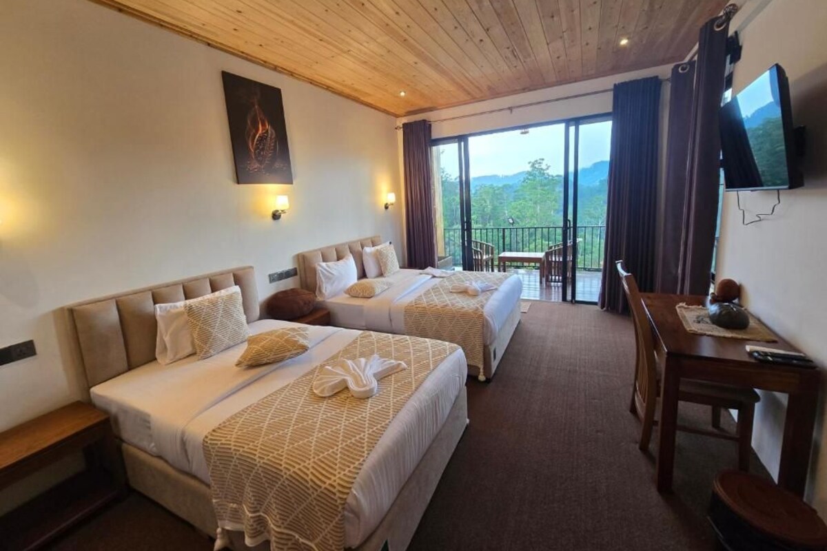 Una habitación de hotel con dos camas, techo de madera, televisor y balcón con vistas.