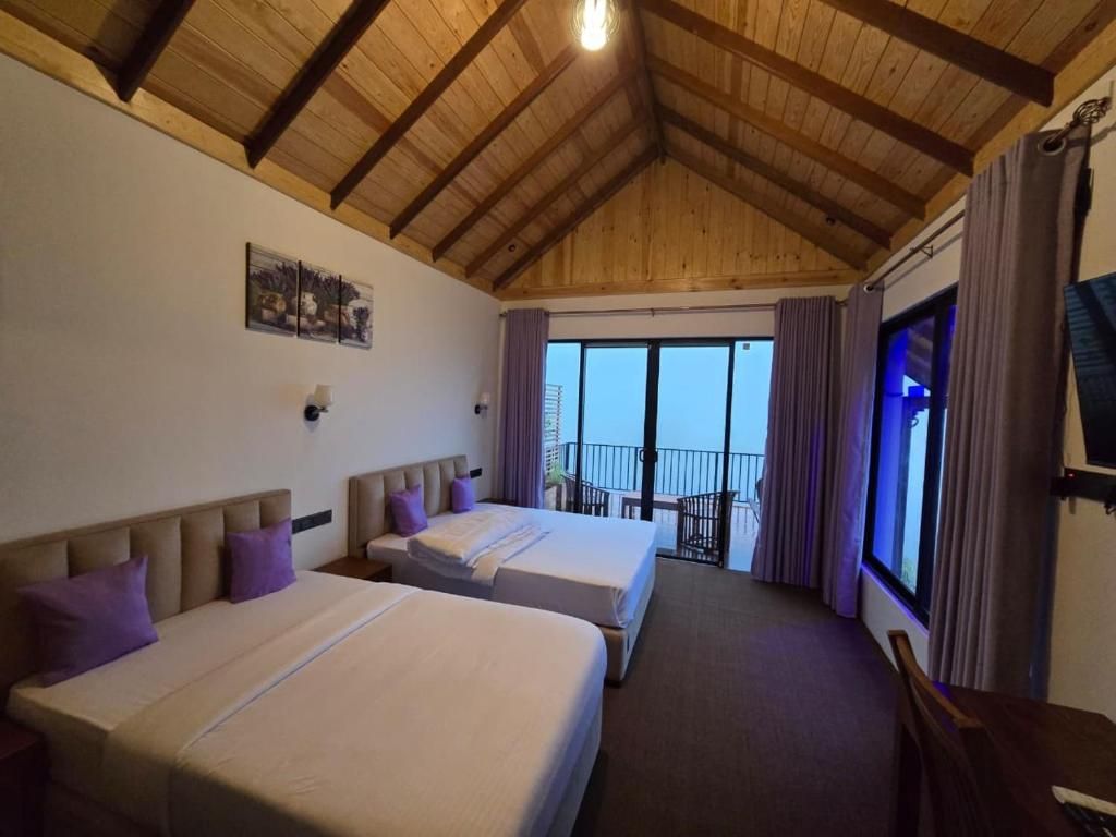 A hotel room with two beds, a balcony, and a wooden ceiling.
