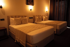 Two twin beds with headboards, a wall-mounted light fixture, and a dark curtain. - Dewpoint Ella (Ella)
