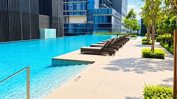 En modern swimmingpool med solstolar och en klarblå himmel.