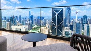 A modern hotel room with a panoramic city view, a round table, and a comfortable seating area. - Skyline Embassy KLCC By Skyblue Suites (Kuala Lumpur)