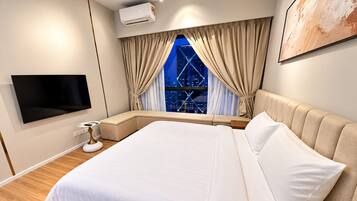 A modern bedroom with a large bed, a flat-screen TV, an air conditioning unit, and a window with curtains.