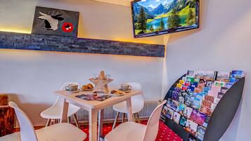 A cozy room with a table set for two, a star-shaped centerpiece, and a wall-mounted TV displaying a scenic landscape.