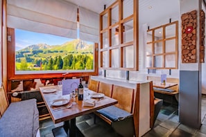 Ein Restaurant mit großen Fenstern und Blick auf die Berge, Holzmöbeln und einem Menüständer.