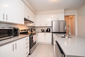 Een moderne keuken met witte kasten, roestvrijstalen apparatuur en een ingebouwde oven.
