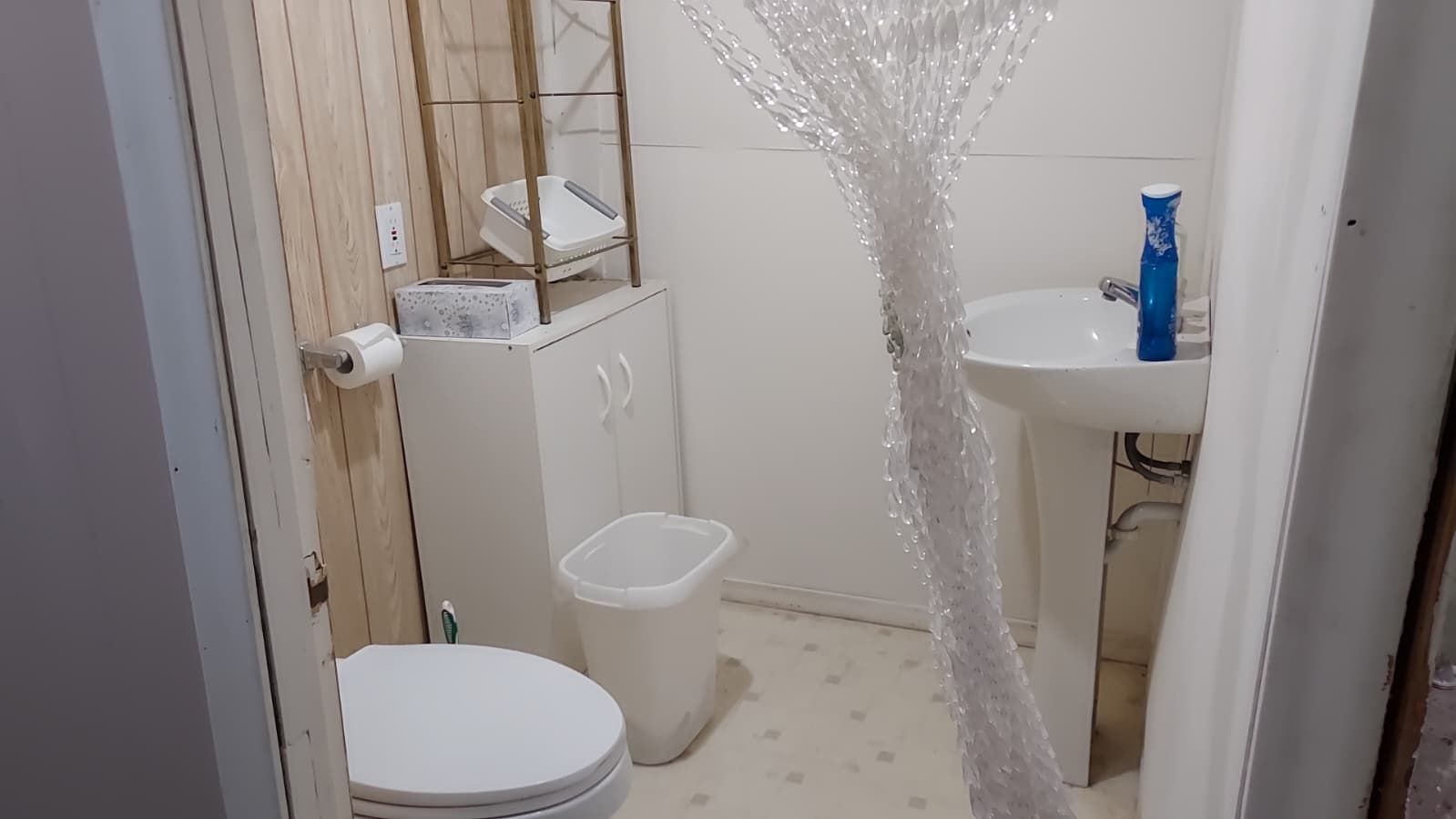A small bathroom with a toilet, a sink, and a shower area.